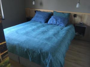a bedroom with a large bed with a blue comforter at Auberge Sans Souci in Valkenburg