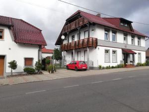 RozwadzaBella Patria的停在白色房子前面的红色汽车