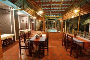 a restaurant with a table and chairs and a swimming pool at Cure Monastery Family Resort in Maraiyūr
