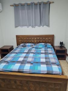 a bed with a blue and white plaid blanket at Arava Hostel in Eilat