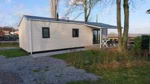 een klein wit tiny house met een terras bij Chalet Camping Natuurlijk Limburg in Remersdaal