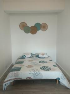 Bett in einem Zimmer mit einer weißen Wand in der Unterkunft T2 - 2 à 3 personnes - draps et serviettes en option in Lorette