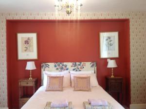 1 dormitorio con 1 cama grande y pared roja en La Grange Terrou, en Saint-Germain-de-Confolens