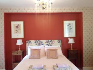 a bedroom with a large bed with a red wall at La Grange Terrou in Saint-Germain-de-Confolens