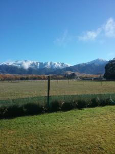 a fence in a field with mountains in the background at Best view on Westview in Hanmer Springs