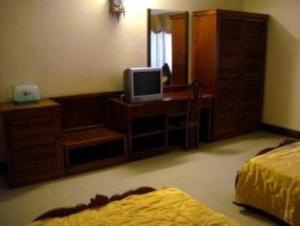 a bedroom with a desk with a television and a bed at Star Hotel in Battambang