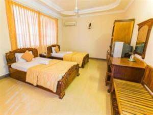 una camera d'albergo con due letti e una televisione di Star Hotel a Battambang