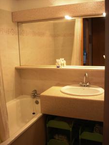 a bathroom with a sink and a mirror and a tub at Cosy at L'Atrey La Tania in Courchevel