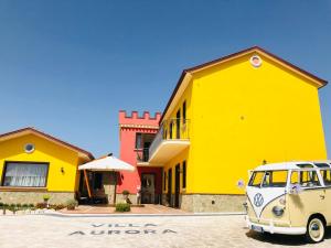 uma carrinha velha estacionada em frente a um edifício amarelo em Villa Aurora em Villanova del Battista