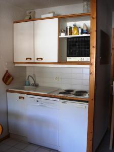 una cucina con armadi bianchi e piano cottura di Cosy at L'Atrey La Tania a Courchevel