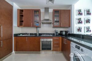a kitchen with wooden cabinets and a stove top oven at Dream Inn Apartments- West Wharf Tower Canal View in Dubai
