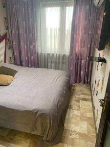 a bedroom with a bed with purple curtains and a window at Appartment Tashkent in Tashkent