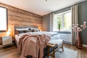 a bedroom with a wooden accent wall at Harzfalke Apartment - Ankommen und wohlfühlen. in Wieda
