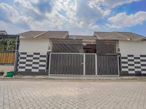 a house with a black and white checkered fence at OYO 90684 Happy Homestay Syariah in Malang