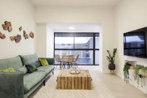 ein Wohnzimmer mit einem grünen Sofa und einem Tisch in der Unterkunft RENOVATED LARGE 3RM APARTMENT 5 MIN FROM THE BEACH in Tel Aviv