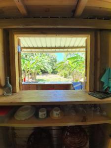 a room with a window and a shelf with cups and plates at Le Chalet, Eco Farm Stay in Vieux Grand Port