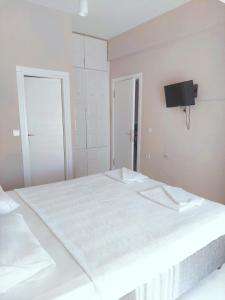 a bedroom with a large white bed with a tv on the wall at Eser Apart Dalyan in Ortaca