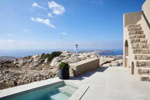 osoba stojąca na skraju klifu patrząca na ocean w obiekcie Santorini Sky, The Lodge w mieście Pirgos