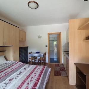 Cet appartement comprend une chambre avec un lit et une table ainsi qu'une cuisine. dans l'établissement Monolocali alla Fontana Termale, à Carano