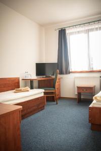 een kamer met 2 bedden, een bureau en een televisie bij Hotel Ach To Tu in Leszno