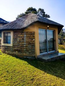 una piccola casa con tetto di paglia e porta di Mountain Aloe Den a Barberton