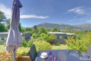 a patio table with an umbrella and mountains in the background at Camping-Hotel de Plein Air Les 2 Bois in Baratier