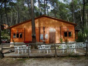 una cabaña de madera con mesas y sillas frente a ella en Cabañas El Robledo en El Robledo