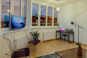 ein Wohnzimmer mit einem TV und einem Schreibtisch mit einem Laptop in der Unterkunft Gesamte Unterkunft über den Dächern Wiens in Wien