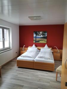 a bedroom with two beds and a red wall at Haus Maximilian in Rammelsbach