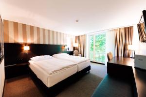 ヴィンタートゥールにあるPark Hotel Winterthurの大きなベッドとデスクが備わるホテルルームです。