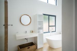 een badkamer met een bad, een wastafel en een spiegel bij Vida Nova Retreat in Hout Baai