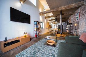 ein Wohnzimmer mit einem Sofa und einem TV an einer Backsteinwand in der Unterkunft L'atelier de Liège: Tranquillité & Effervescence in Lüttich
