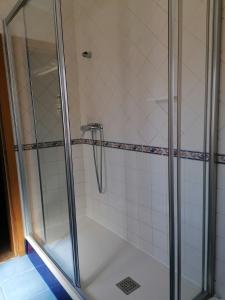 a shower stall with a glass shower door at Hospedaria Dona Maria in Beja