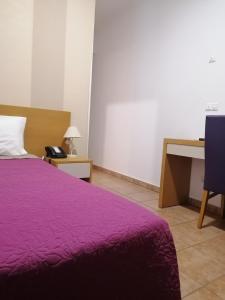 una camera con letto viola e scrivania di Hospedaria Dona Maria a Beja