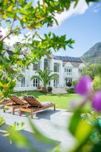 a house with two wooden benches in front of it at Vida Nova Retreat in Cape Town