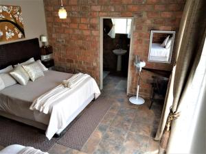 1 dormitorio con cama y pared de ladrillo en Edenville Guesthouse, en Lichtenburg