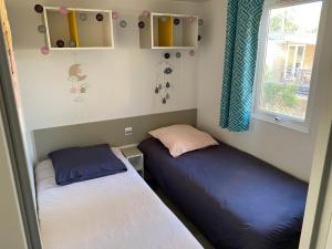 deux lits dans une petite pièce avec une fenêtre dans l'établissement Mobil-Home Camping Club 5* Montalivet, à Vendays-Montalivet