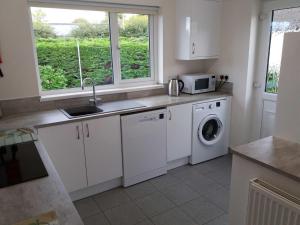 eine Küche mit einer Spüle und einer Waschmaschine in der Unterkunft Lough Conn Holiday Home in Crossmolina