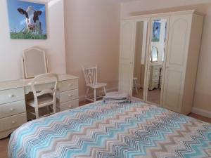 een slaapkamer met een bed en een bureau met een koeienschilderij aan de muur bij Lough Conn Holiday Home by Trident Holiday Homes in Crossmolina