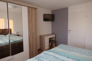 1 dormitorio con 1 cama y escritorio con TV en Ferienwohnung Casa Rosa en Bildstein