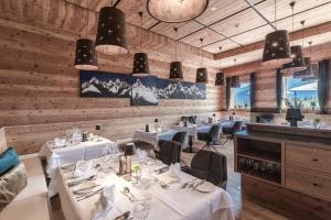 un restaurante con mesas y sillas blancas y paredes de madera en NIDUM - Casual Luxury Hotel en Seefeld in Tirol