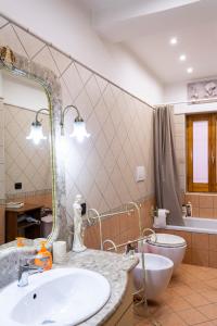 ein Badezimmer mit einem Waschbecken, einem WC und einem Spiegel in der Unterkunft Le Ali del Vento in Cairano