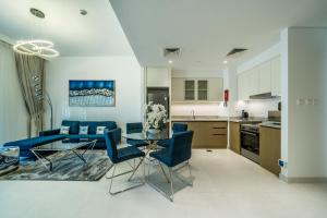 a kitchen and living room with blue chairs and a table at Primestay - Creekside 18 Creek Harbour in Dubai