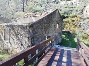 un antiguo edificio de piedra en un puente de madera en Casa do Adro - Serra da Estrela, en Cortes do Meio