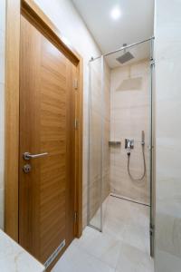 a shower with a wooden door in a bathroom at L L L centar in Zlatibor