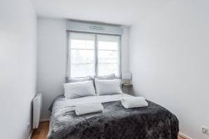a bedroom with a bed with two pillows and a window at Chez patron T4 3BR near Disneyland and train station-Montévrain in Montévrain