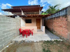 a red table and chairs in front of a brick wall at Chalé Aconchego 1 in Ilhabela
