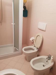 La salle de bains rose est pourvue de toilettes et d'une douche. dans l'établissement B&B La Rocca, à SantʼAgata Feltria