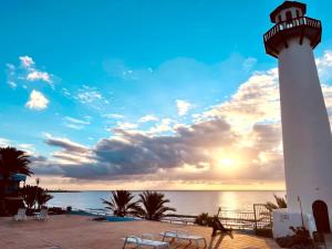 ein Leuchtturm am Strand mit Sonnenuntergang in der Unterkunft VIVIENDA ÚNICA EN PRIMERA LÍNEA DE PLAYA in San Bartolomé de Tirajana