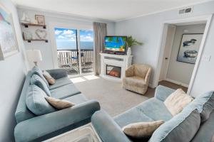un soggiorno con 2 divani blu e una TV di 2BR, 2Bath condo Oceanfront Getaway with pool a Myrtle Beach